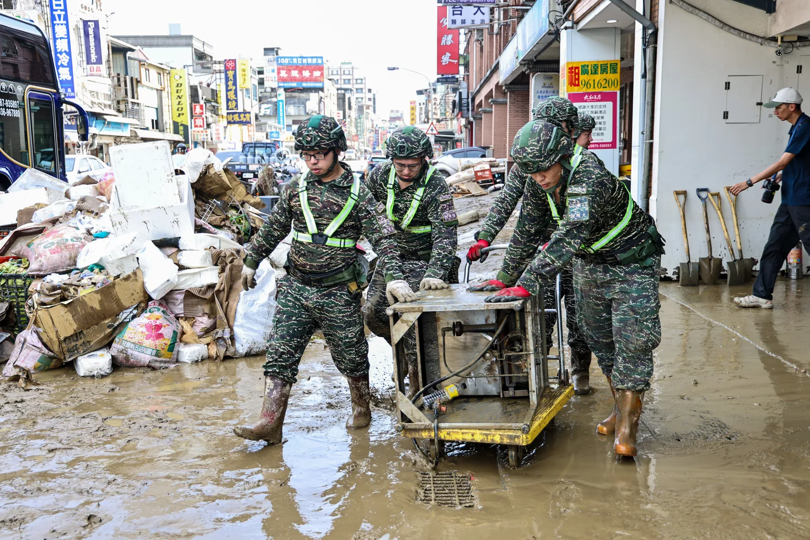 國軍官兵在泥濘街道協力搬運物資，投入災後復原工作