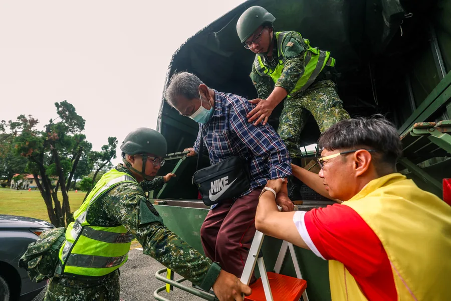 國軍官兵與工作人員攙扶長者離開軍用車輛