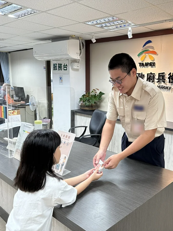替代役役男在臺北市政府兵役局櫃檯將宣導品交給民眾