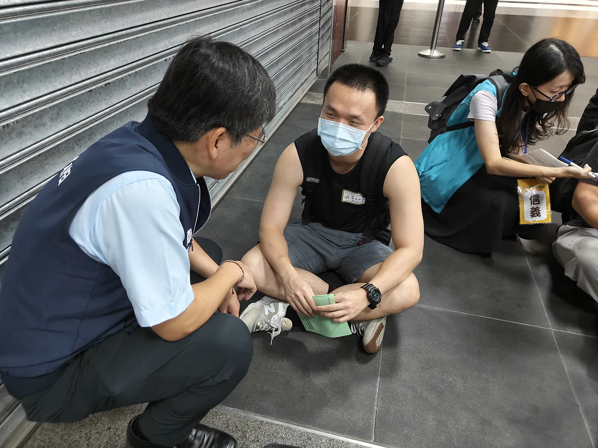 市府代表蹲下與在集合場等候的役男交談
